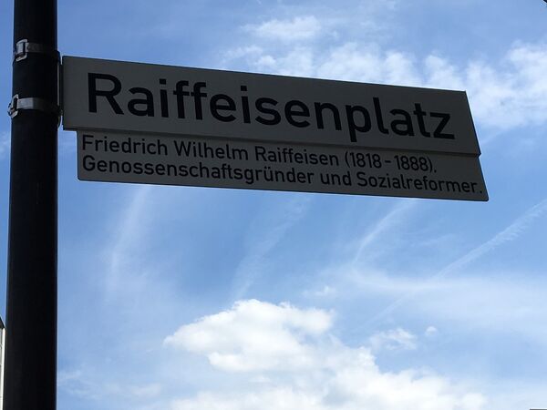 Das neue Raiffeisenplatz-Straßenschild mit Zusatz.